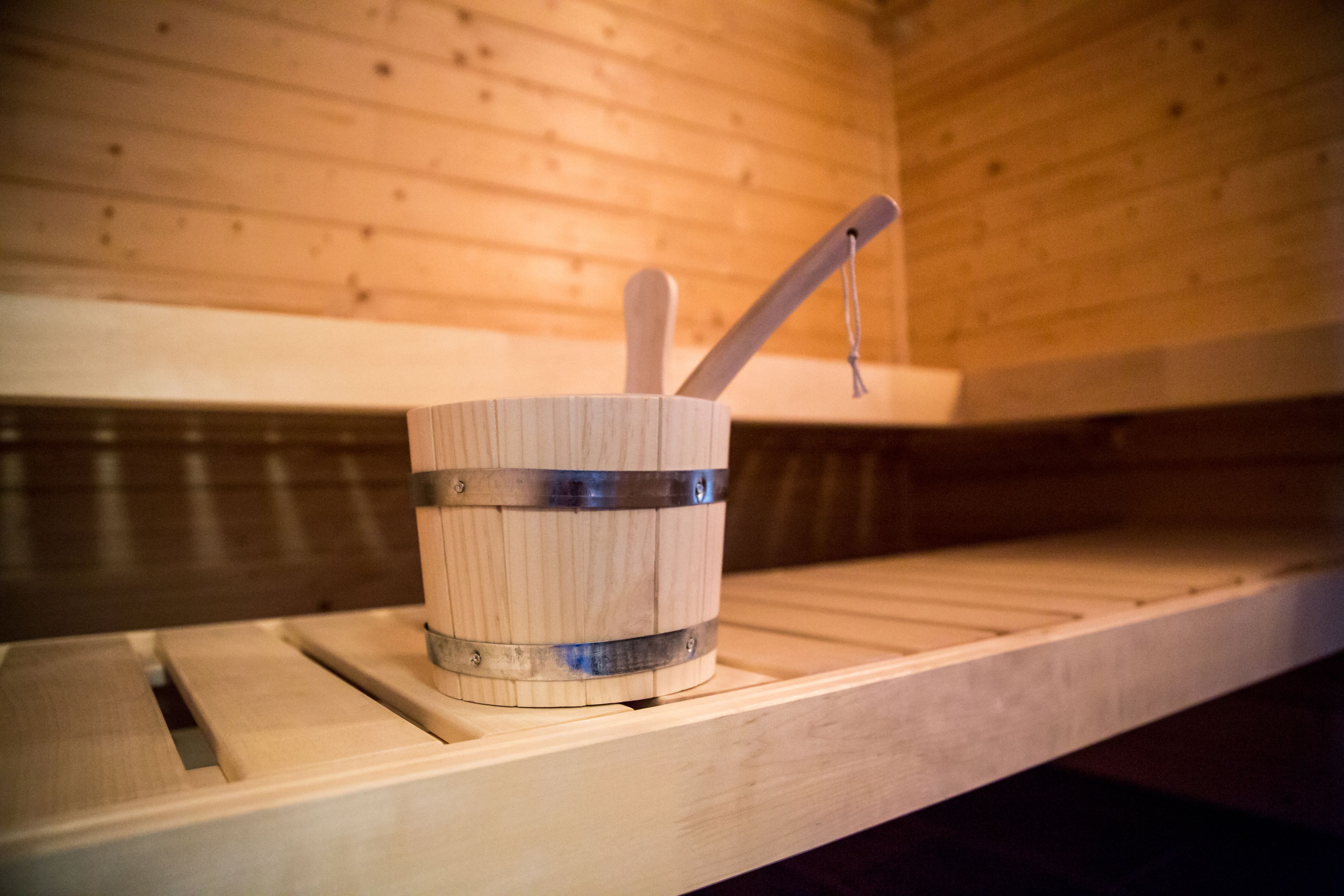 A wooden sauna with a wooden bucket and a wooden ladle on a shelf.