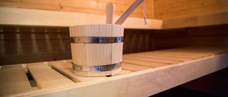 A wooden sauna with a wooden bucket and a wooden ladle on a shelf.