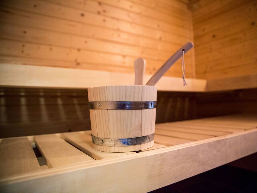 A wooden sauna with a wooden bucket and a wooden ladle on a shelf.