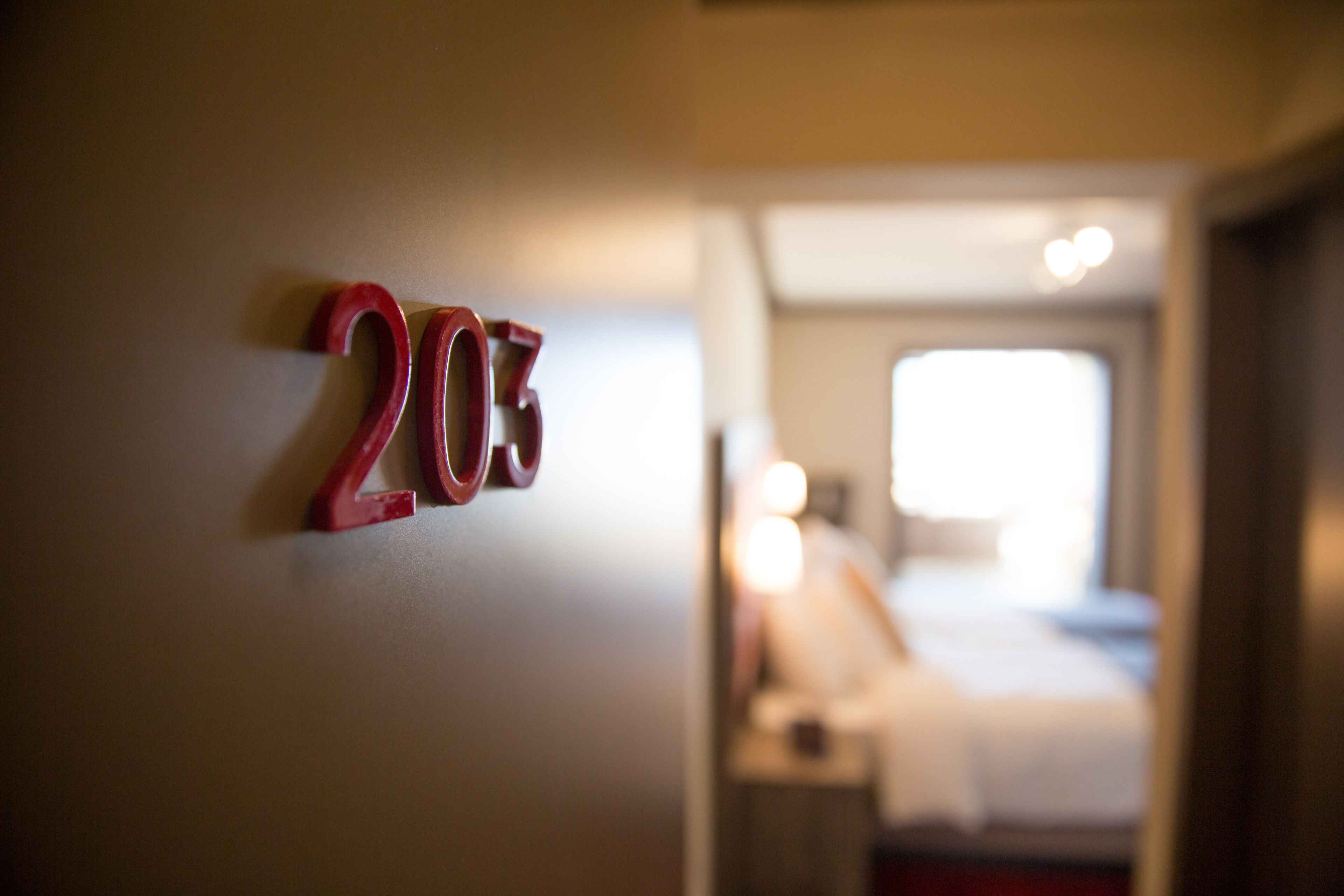 A hotel room number 203 with a bed and a nightstand in the background.