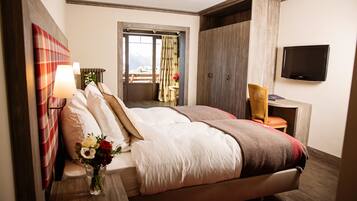 Hotelkamer met een groot bed, een televisie, een bureau met stoel en uitzicht op de bergen.