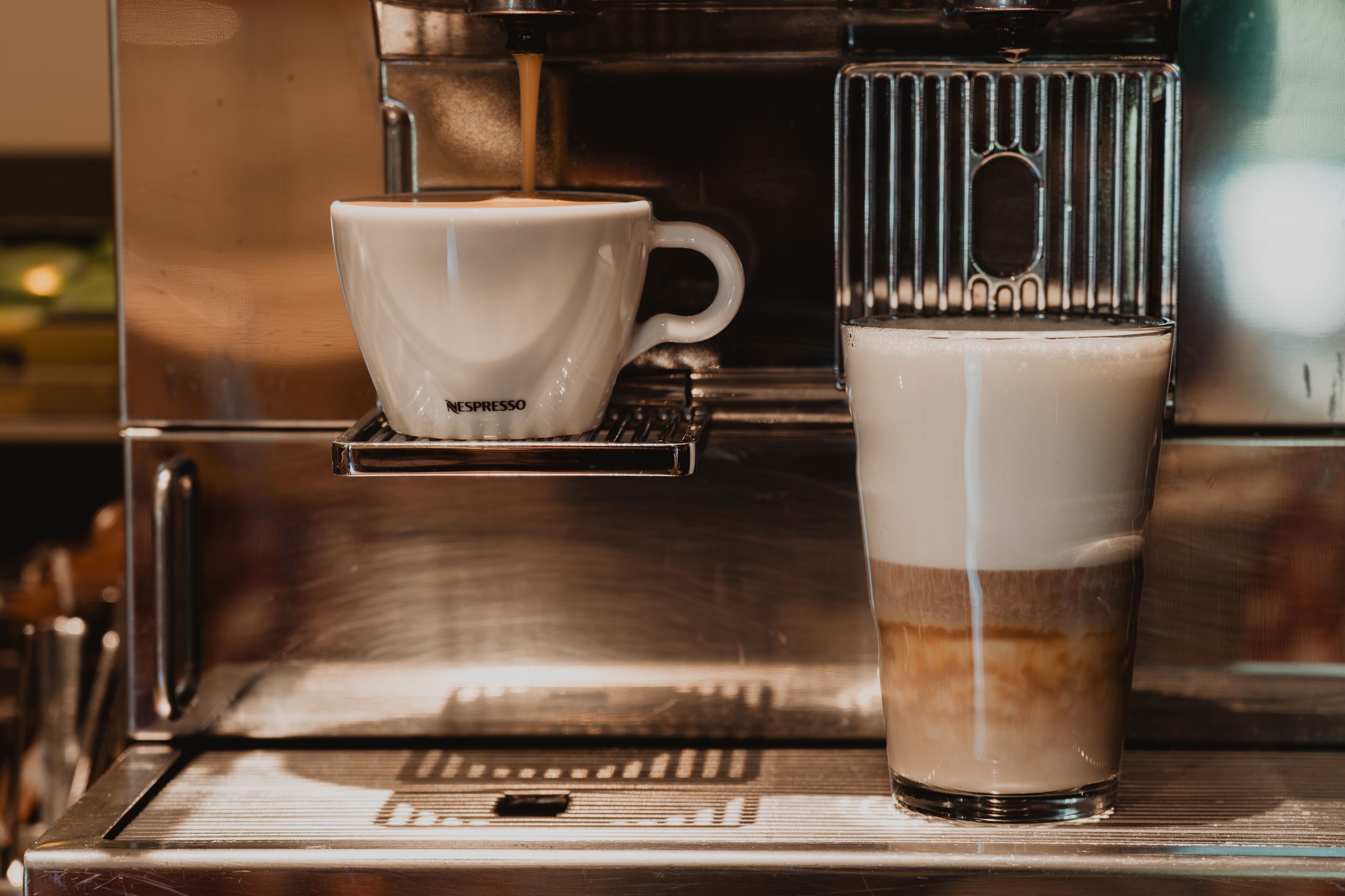 A coffee machine with a cup and a glass of coffee.