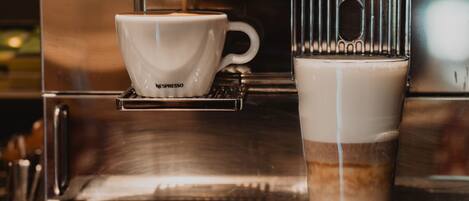 A coffee machine with a cup and a glass of coffee.