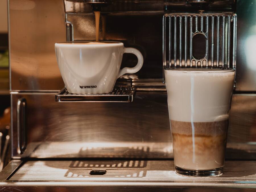 A coffee machine with a cup and a glass of coffee.
