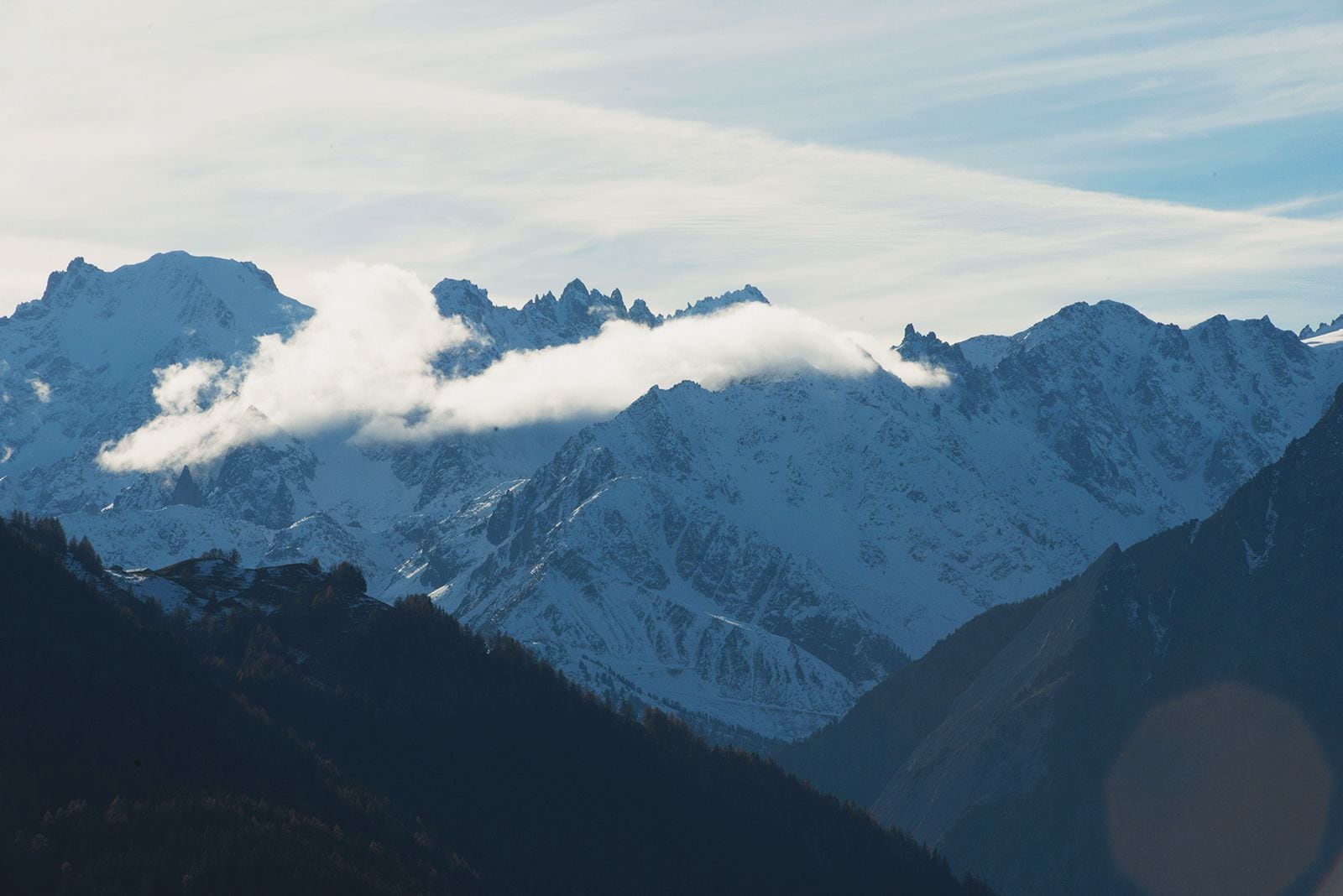 Un paisaje montañoso con picos nevados y un valle.