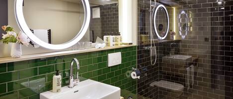 A modern bathroom with a large mirror, a sink, a toilet, and a shower area.