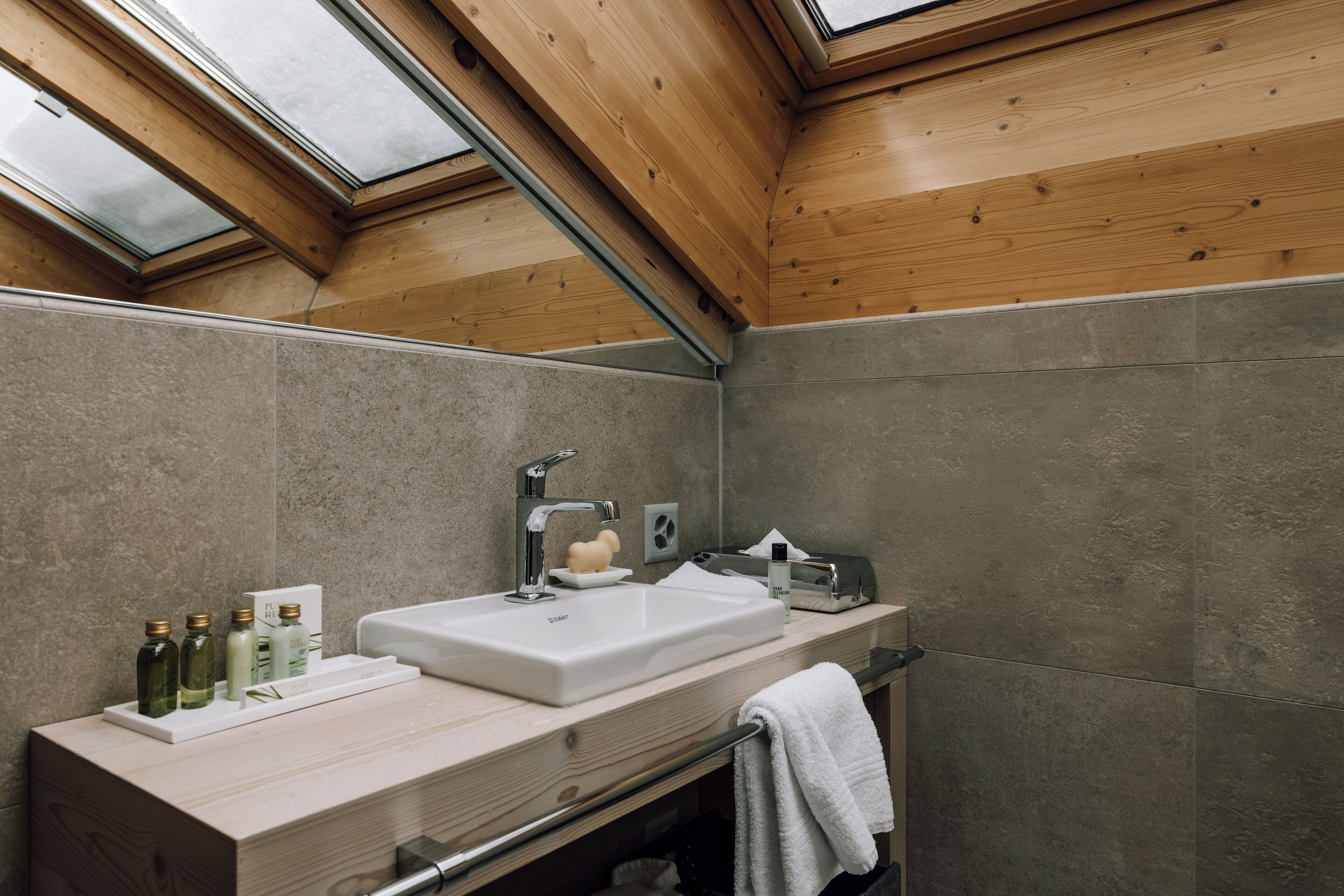 Ein modernes Badezimmer mit Dachfenster, einem großen Waschbecken und einem hölzernen Waschtisch.