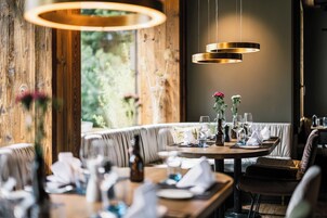 Comedor con una mesa redonda para dos personas, paredes de madera y lámparas colgantes.