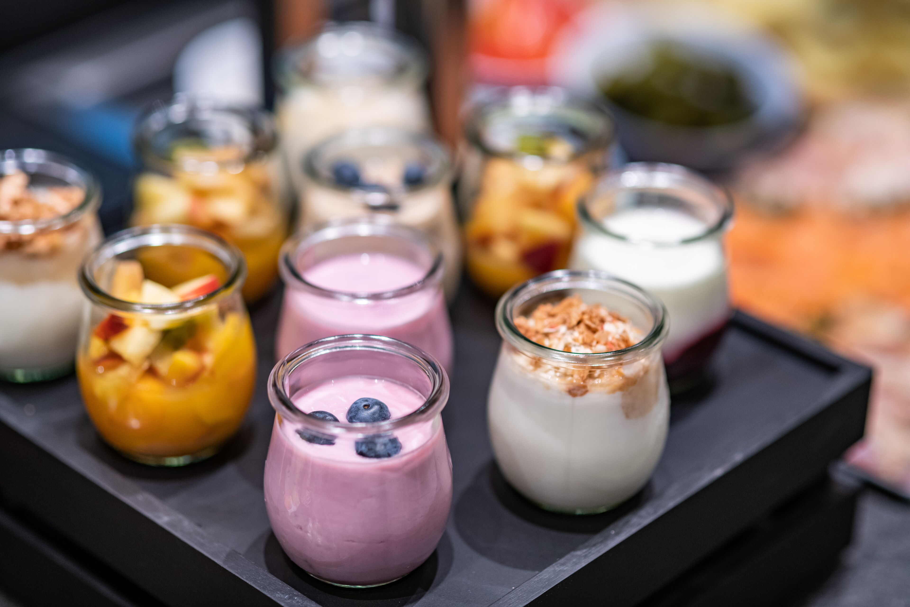 A variety of small glass containers with different types of yogurt topped with fruits and granola.