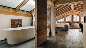 Un baño moderno con una bañera independiente, detalles de madera y un tragaluz.