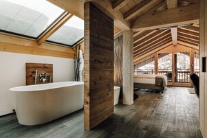 Un baño moderno con una bañera independiente, detalles de madera y un tragaluz.
