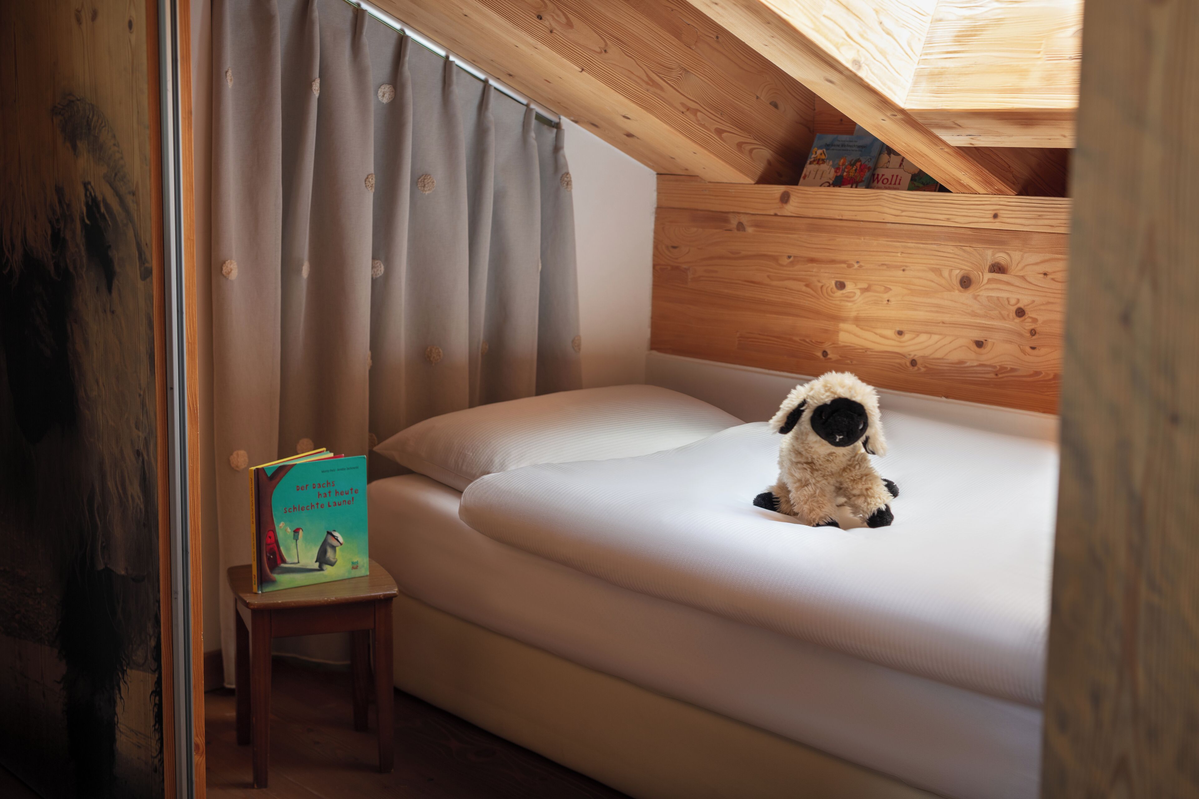 Una habitació acollidora amb un llit, una taula petita i un joguet de peluix.