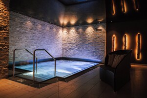 Un área de spa con un jacuzzi, una silla y una pared de ladrillo.