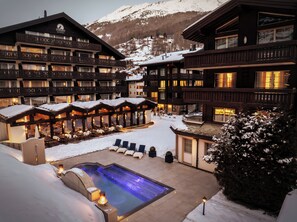 A hotel with multiple balconies, a pool area, and snow-covered surroundings.