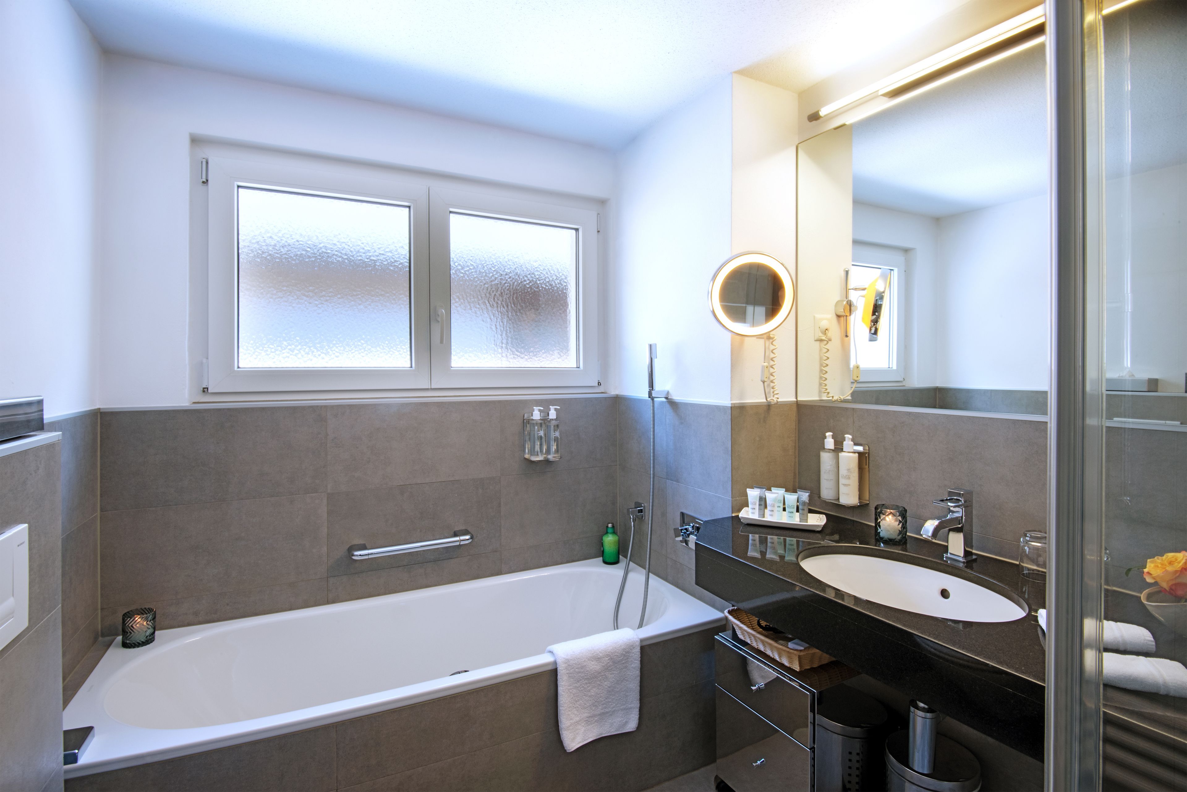 A modern bathroom with a bathtub, a vanity with a sink, and a large mirror.