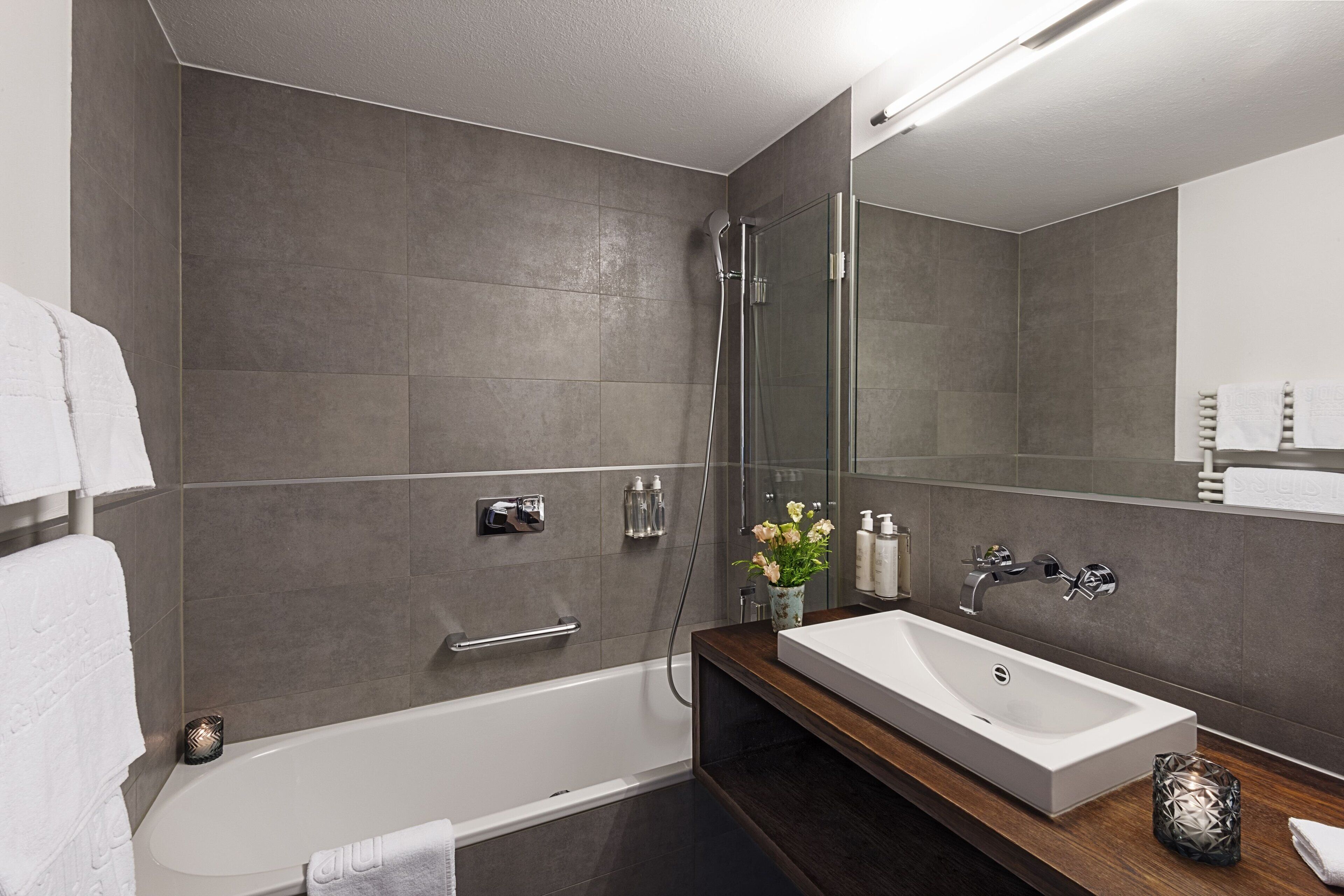 A modern bathroom with a large bathtub, a separate shower area, and a vanity with a sink and mirror.