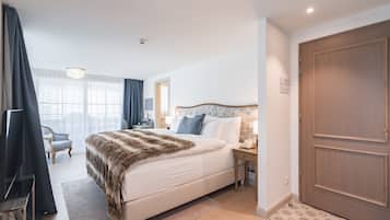 Una camera d'albergo con un letto grande, un comodino, una sedia e una porta in legno.