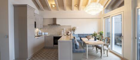 Una cocina moderna con una isla integrada, un comedor con banco y un amplio ventanal con vistas.