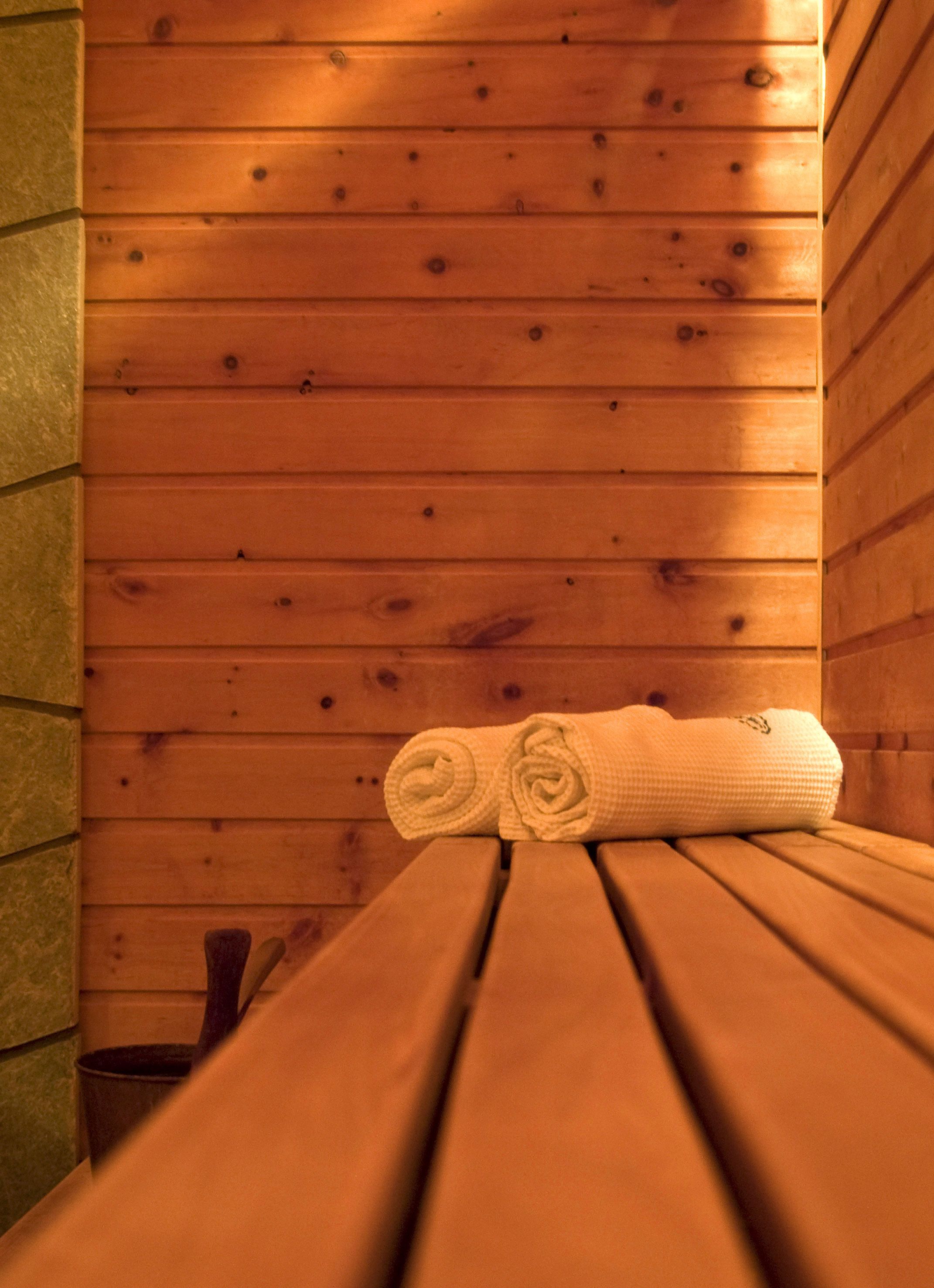 Eine Holzbank mit einem aufgerollten Handtuch in einer Holzhütte.