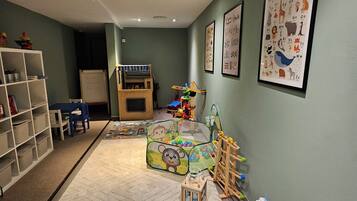 Quarto ideal para crianças, com espaço de brincadeiras, estante de livros e cartazes educativos na parede.