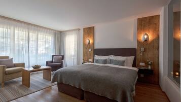 A modern bedroom with a large bed, two bedside tables, a nightstand, a sofa, and a chair.