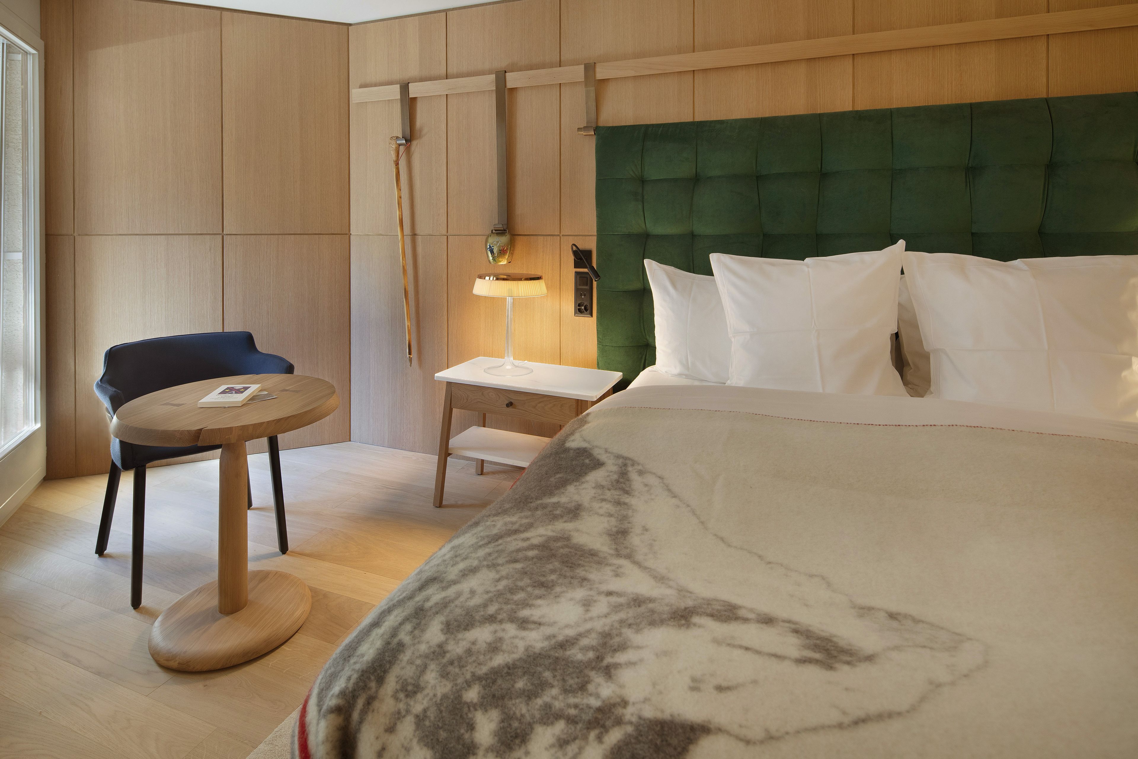 Une chambre d’hôtel avec un lit, une chaise, une petite table et une lampe.