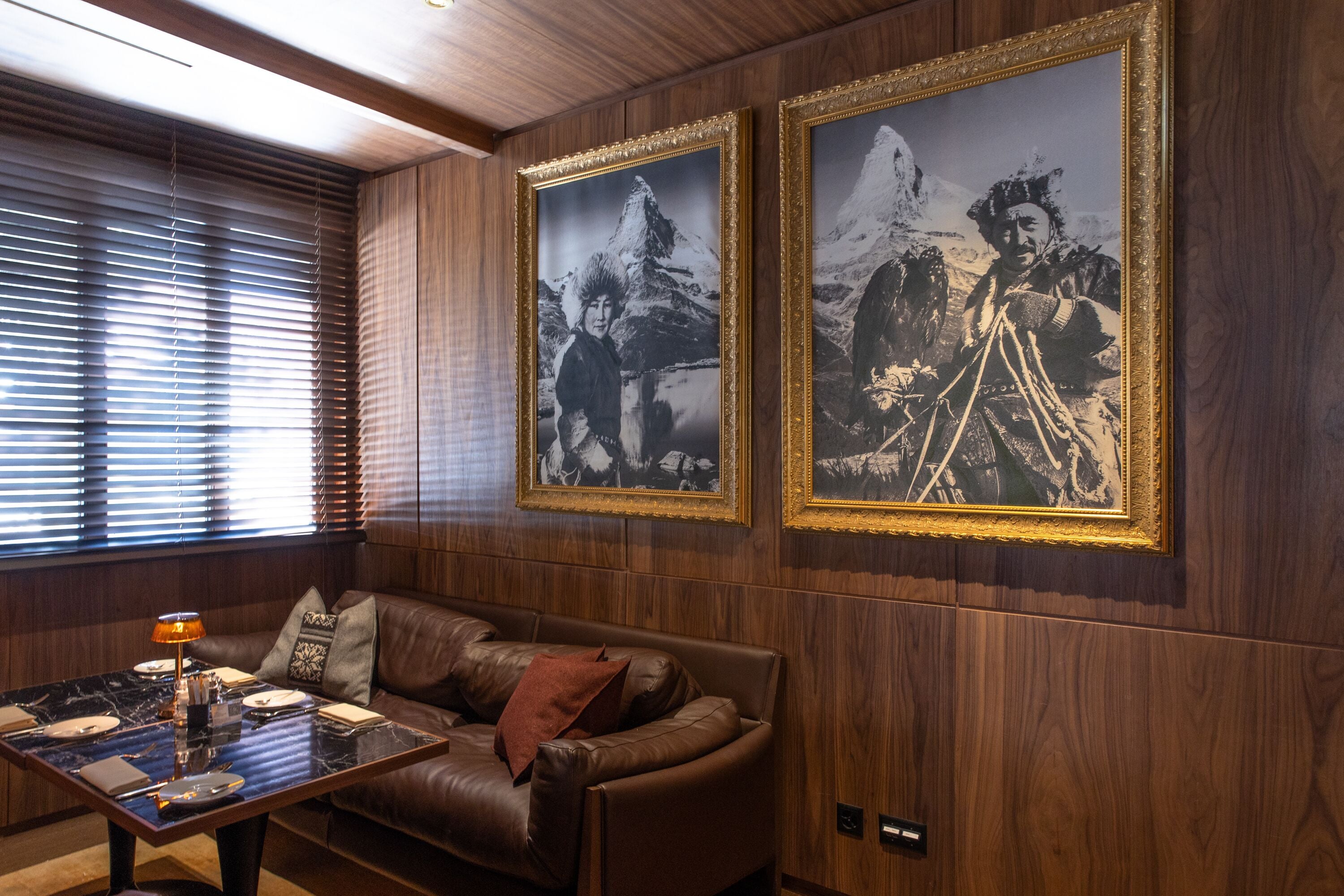 Una habitación con un revestimiento de madera, un sofá de cuero, una mesa de centro y dos cuadros enmarcados.