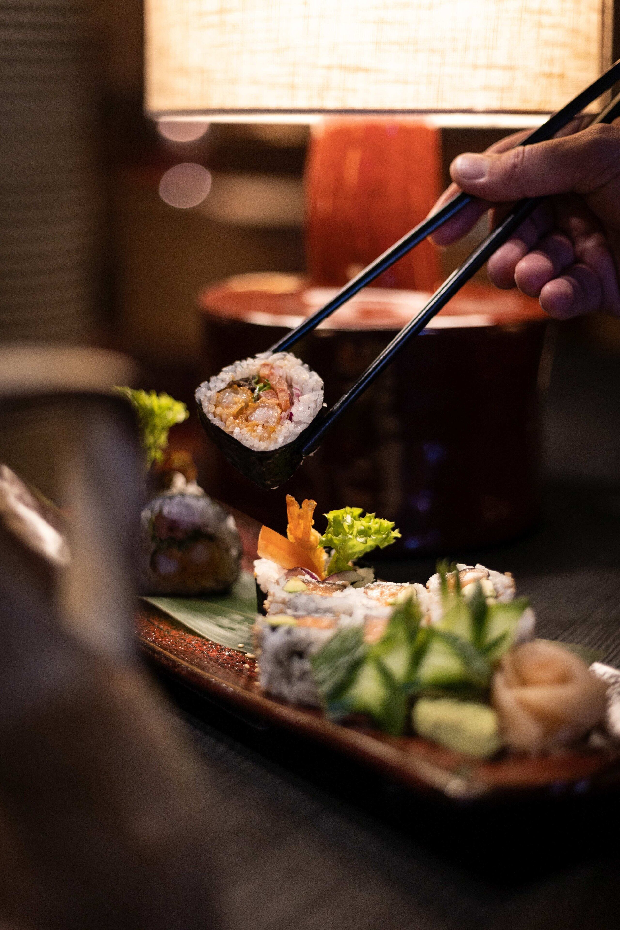 Una bandeja de sushi con diferentes tipos de sushi y una lámpara al fondo.