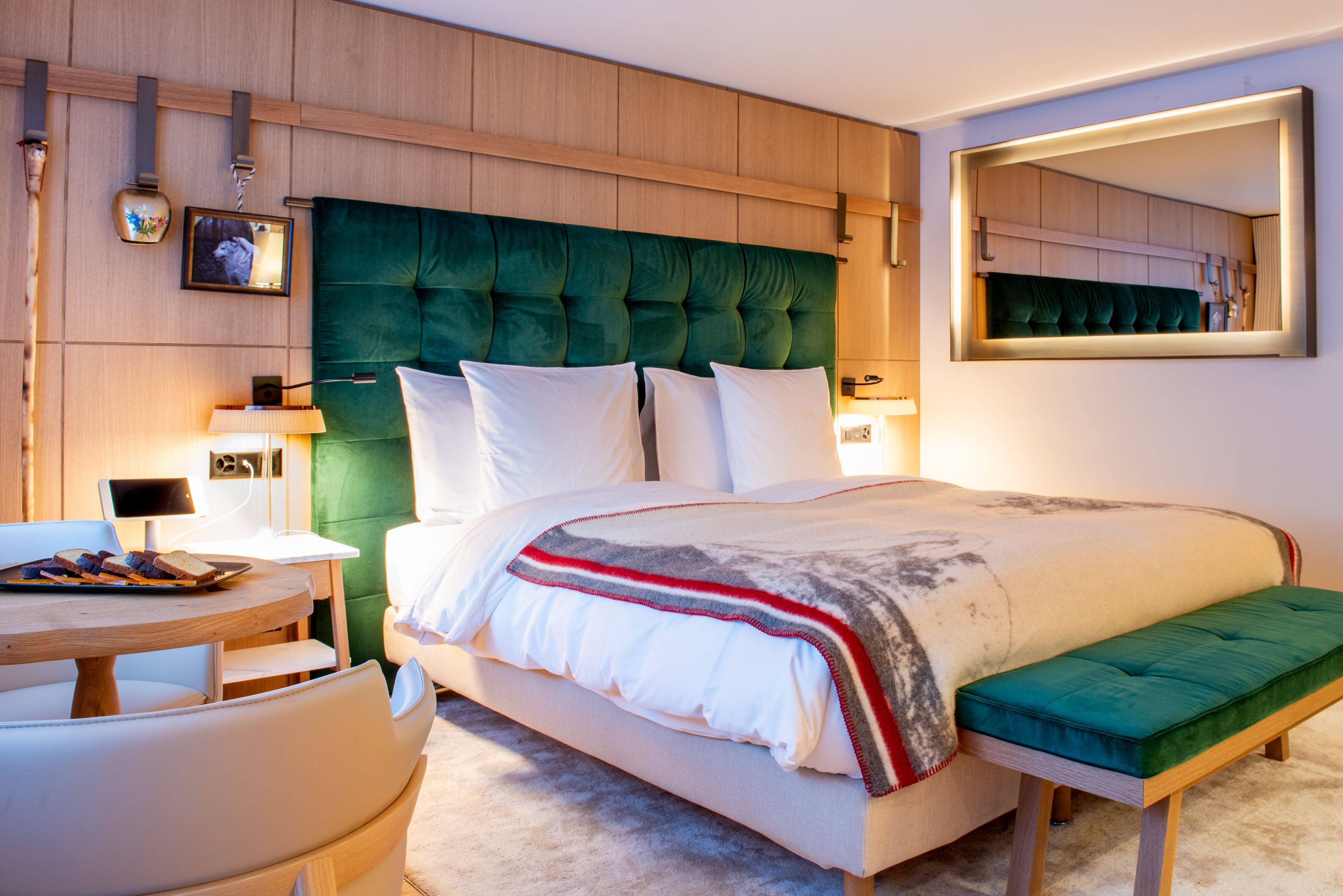 A modern bedroom with a large bed, a bedside table, a chair, and a bench.