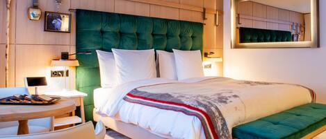 A modern bedroom with a large bed, a bedside table, a chair, and a bench.