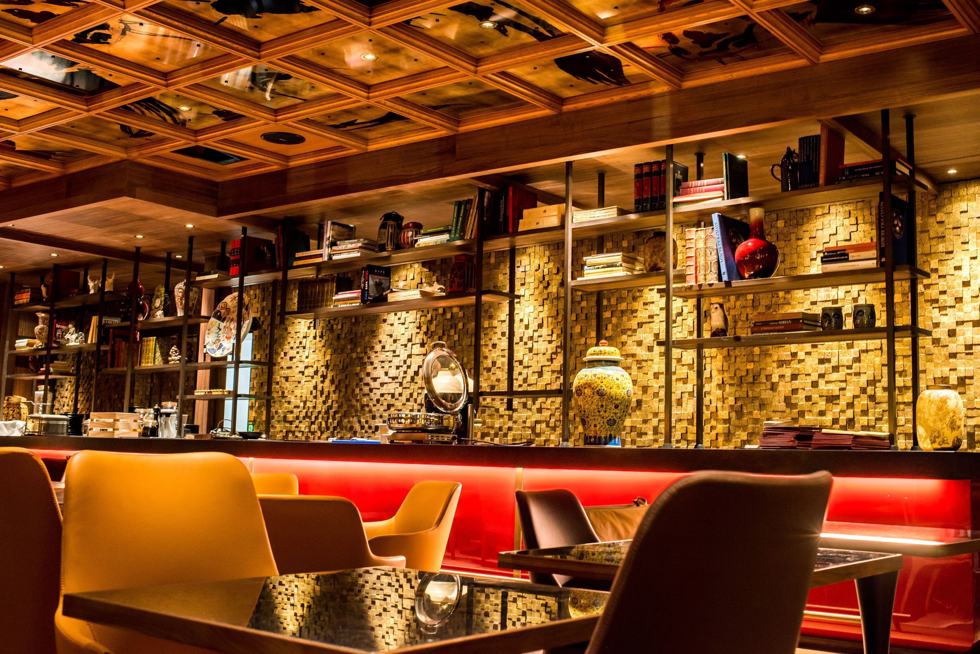 A restaurant with a red booth seating area, wooden ceiling with animal carvings, and shelves with books and decorative items.