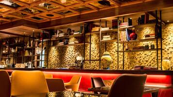 A restaurant with a red booth seating area, wooden ceiling with animal carvings, and shelves with books and decorative items.