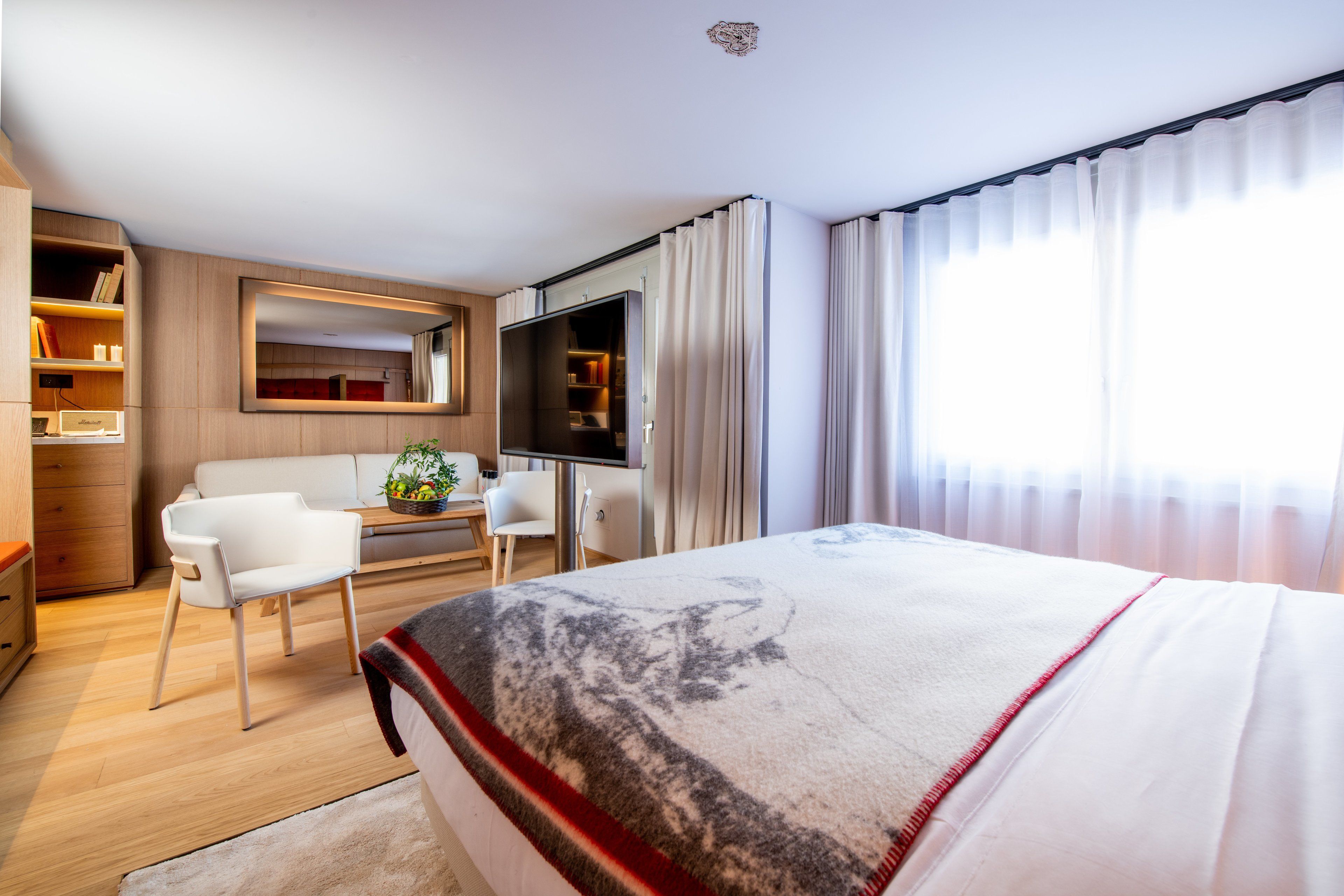 Et hotelværelse med en stor seng, et skrivebord med stol, en sofa, et fjernsyn og en garderobe.