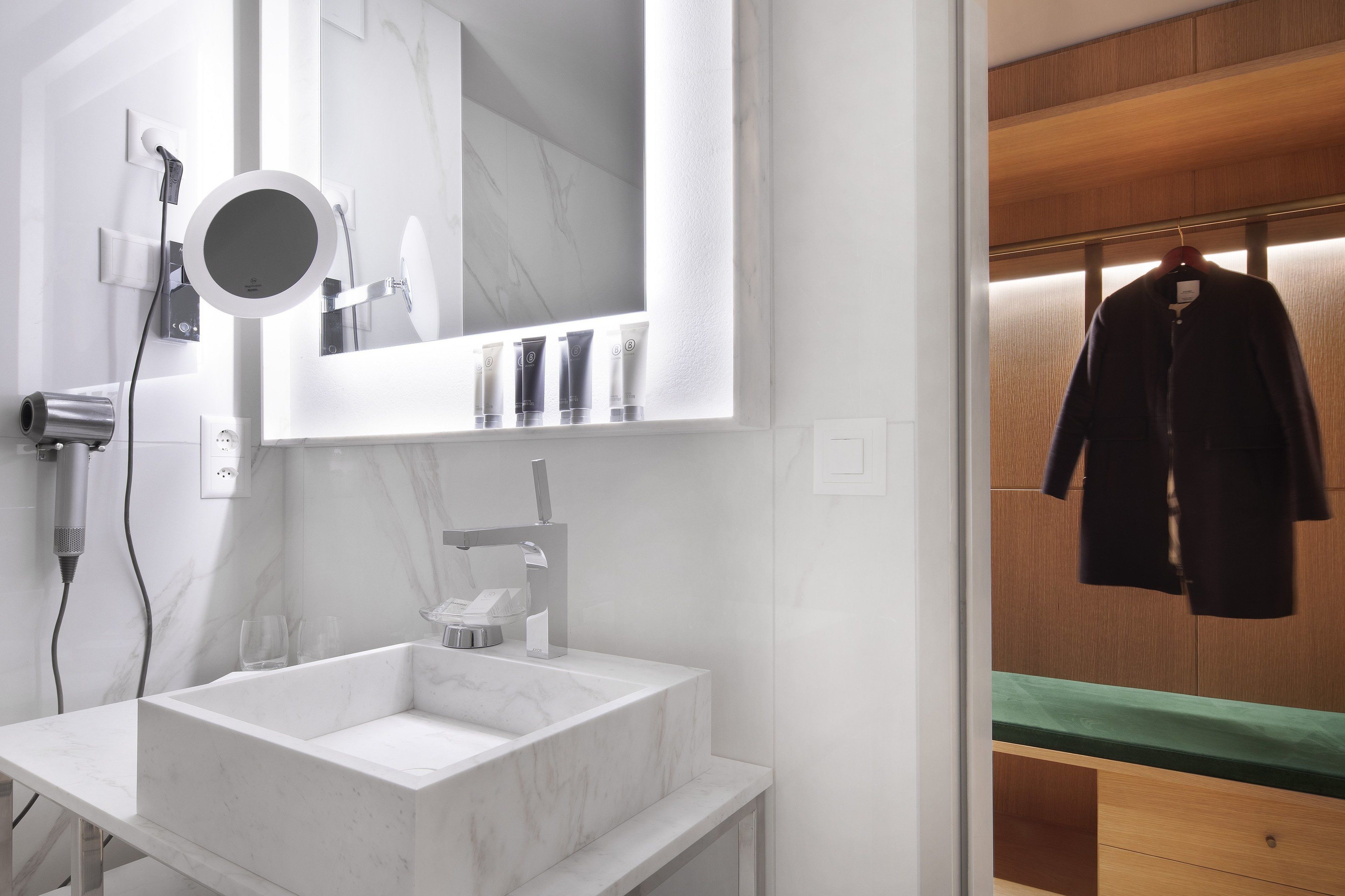 A bathroom with a marble sink, a mirror, and a hairdryer.