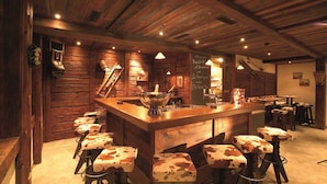 Una zona de bar rústica con paredes de madera, un mostrador central y taburetes con estampado de vaca.