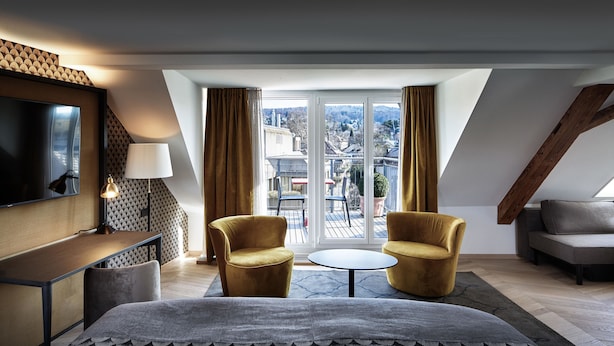 A modern hotel room with a bed, two armchairs, a small table, a TV, and a balcony with a view. - Sorell Boutique-Hotel Seefeld Zürich (Zürich)