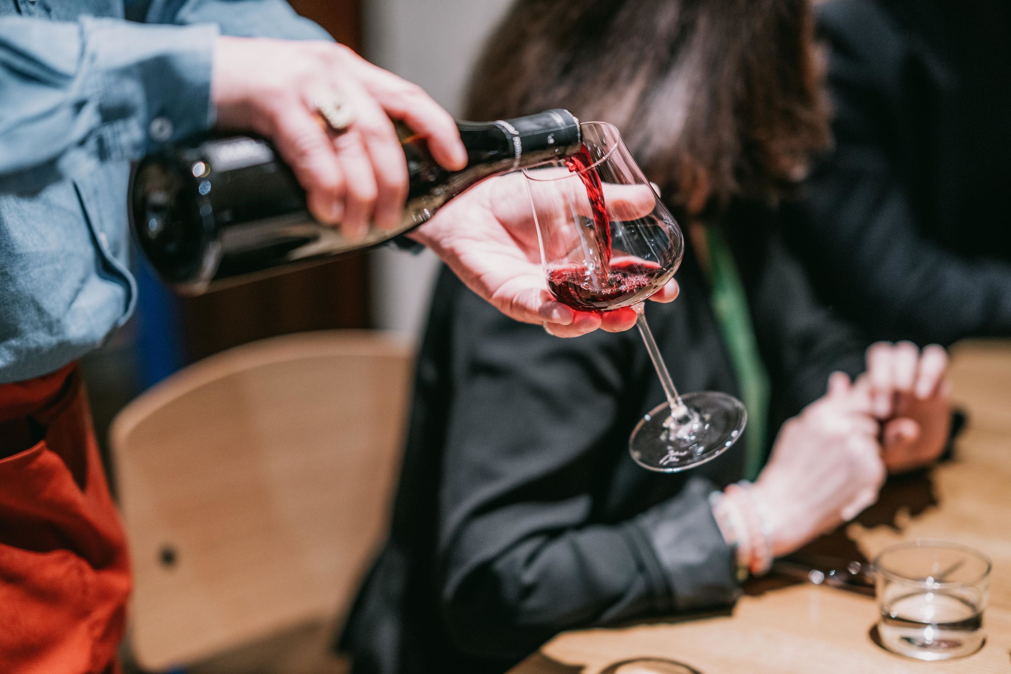 Una persona sirviendo vino tinto en una copa.