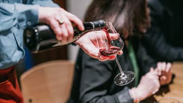 Una persona sirviendo vino tinto en una copa.