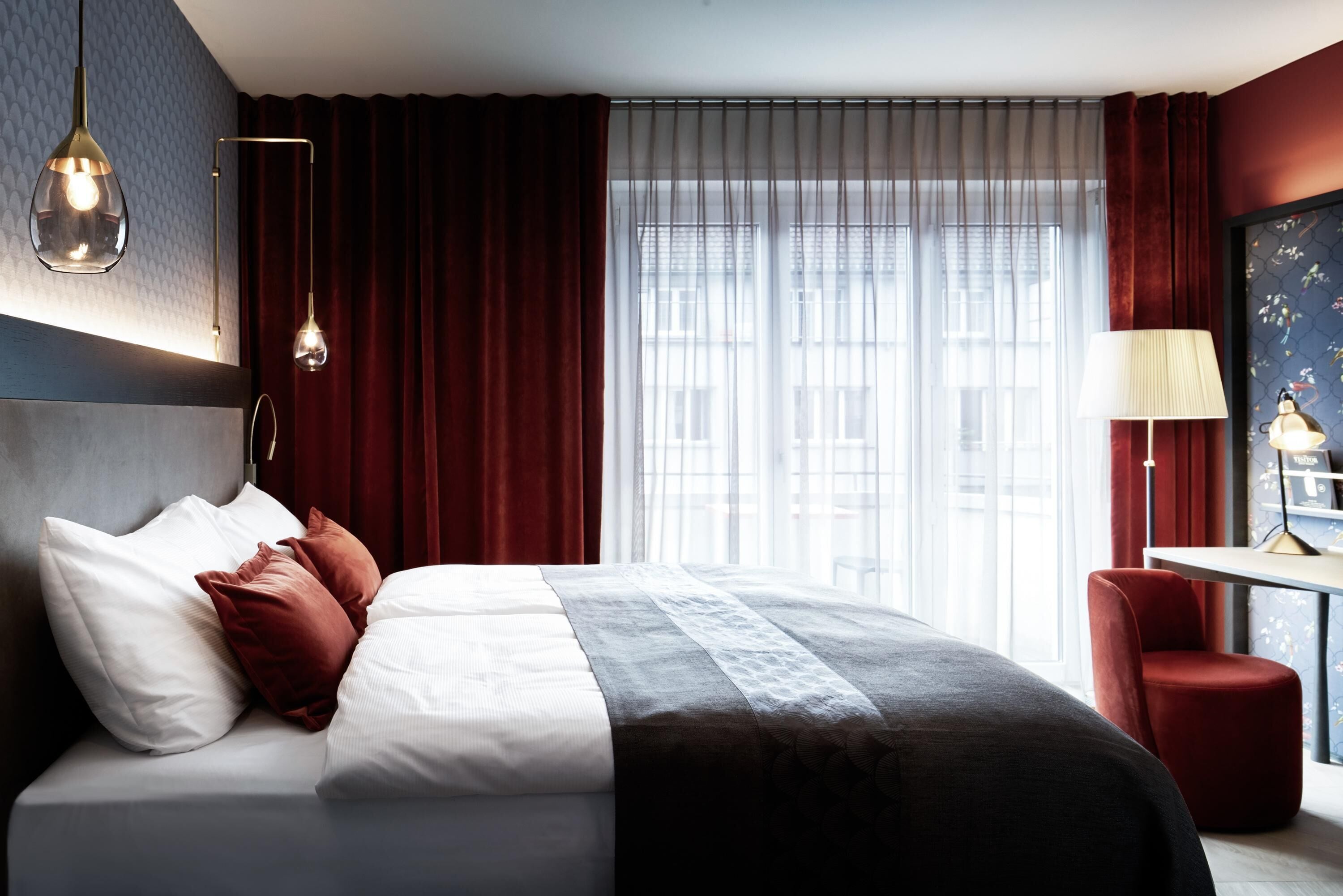 Una habitación de hotel con cama, escritorio y ventana con cortinas.