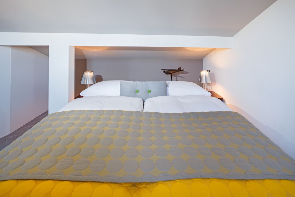 A bed with a patterned bedspread, two bedside lamps, and a decorative airplane on the headboard.