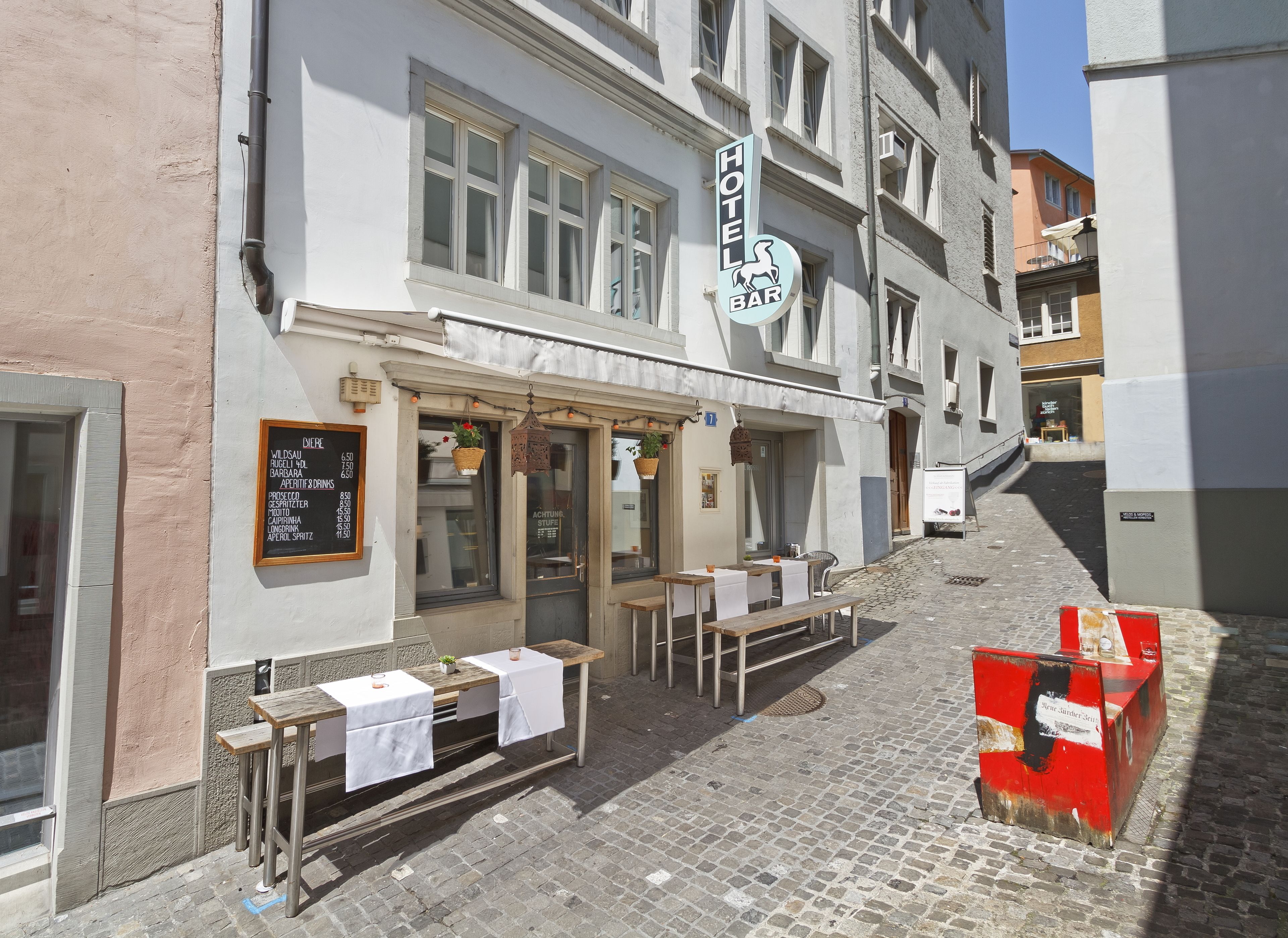 A hotel bar with outdoor seating on a cobblestone street.