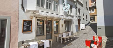 A hotel bar with outdoor seating on a cobblestone street.