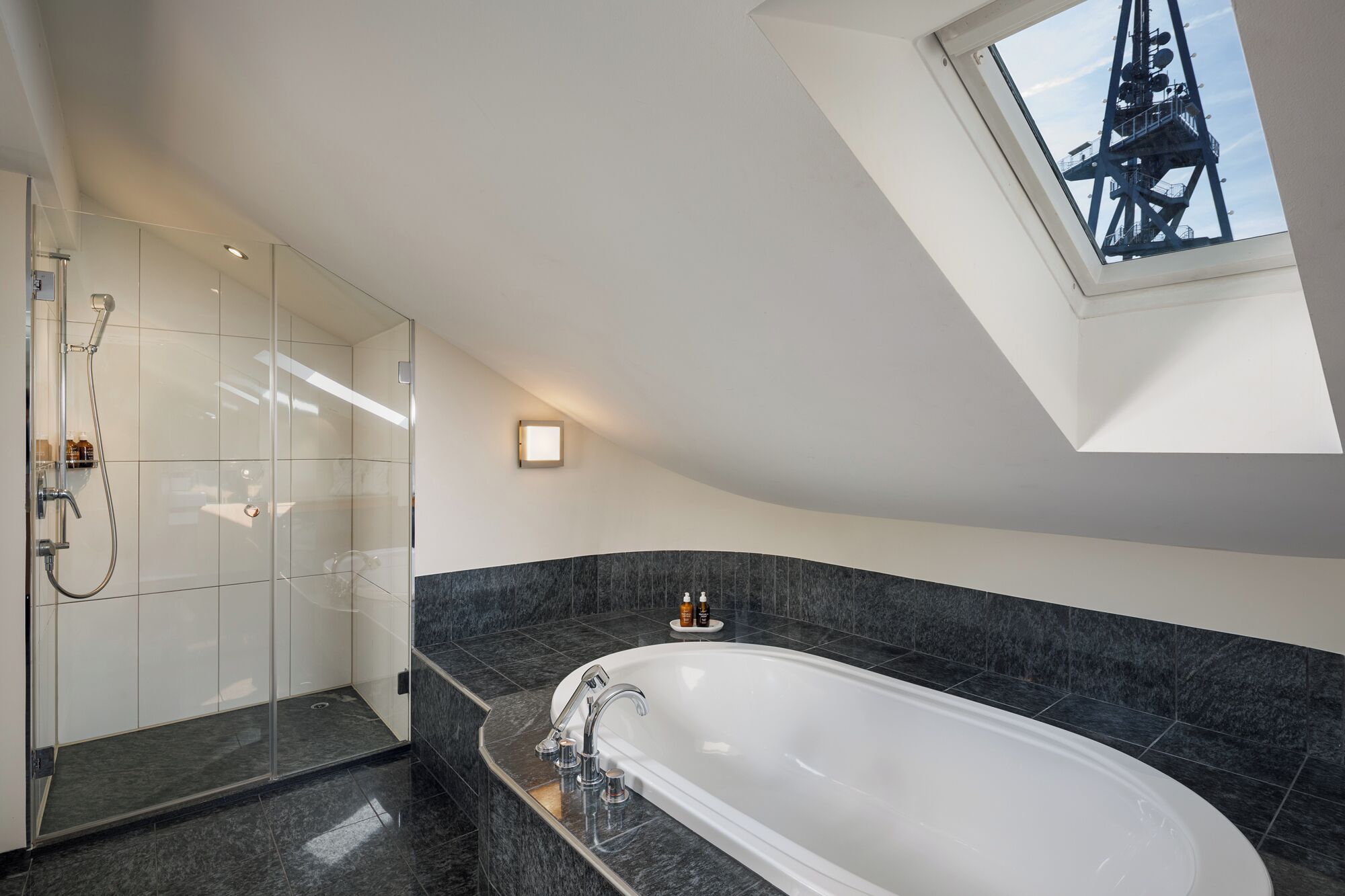 Ein modernes Badezimmer mit freistehender Badewanne, einer Glasdusche und einem Oberlicht.