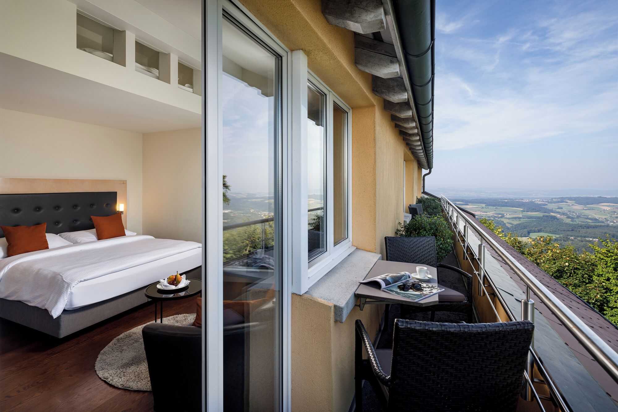 Une chambre avec un grand lit et un balcon équipé d’une table et de chaises.