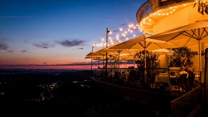 A restaurant with outdoor seating, a curved balcony, and string lights. - UTO KULM - Top of Zurich (Zürich)