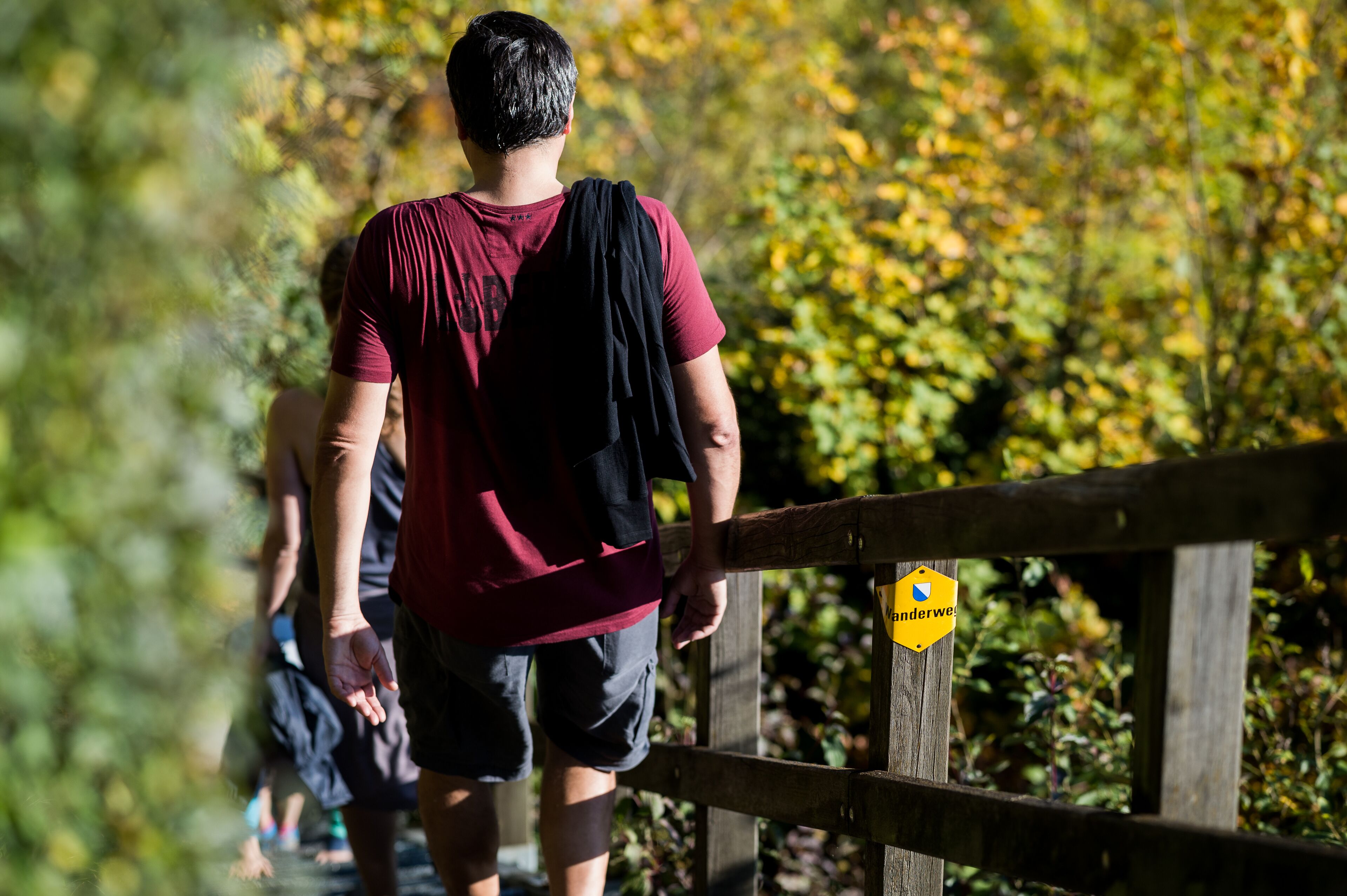 A person walking on a wooden bridge with a yellow sign that reads "Underway".