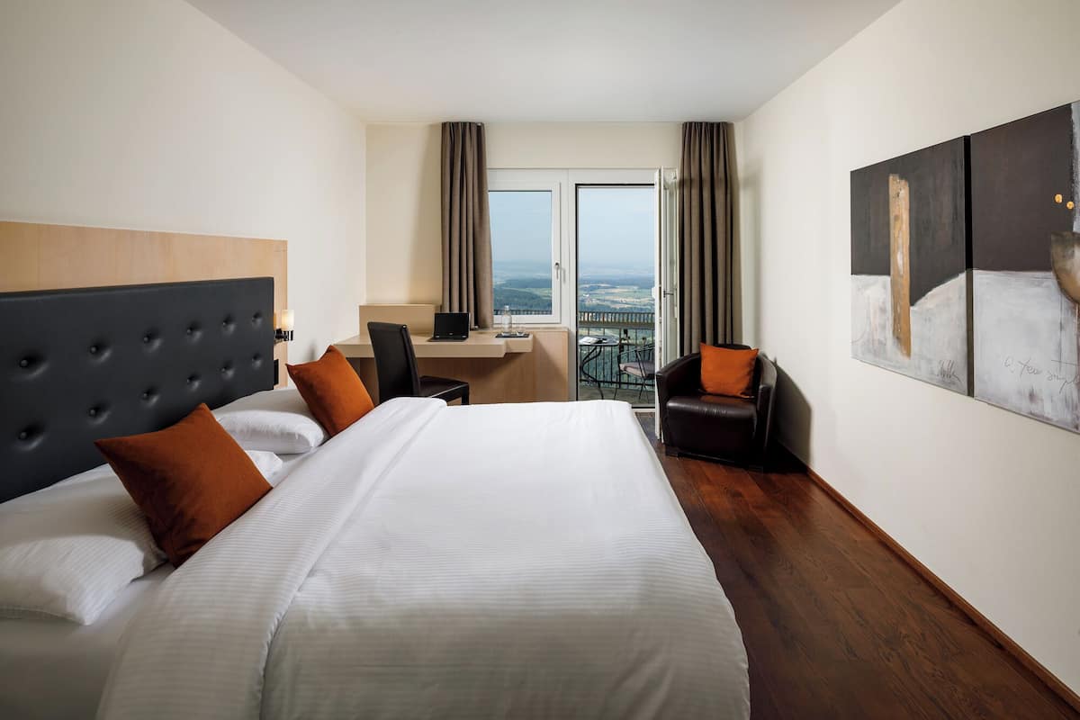 Une chambre d’hôtel avec un grand lit, un bureau, un ordinateur portable et une vue sur la ville.