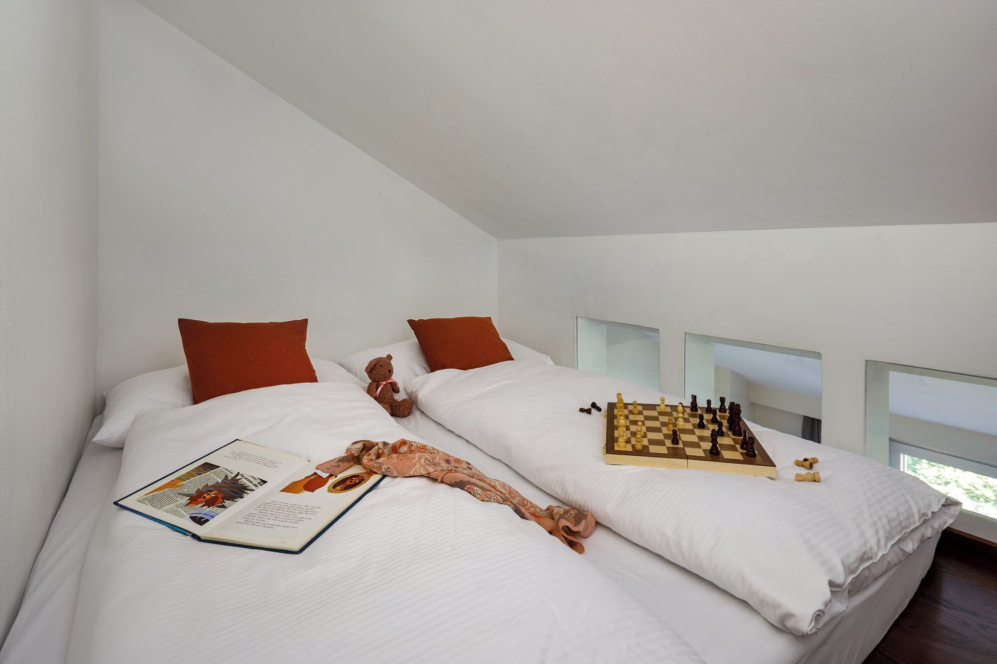 Una camera da letto moderna con due letti, una scacchiera e un libro.