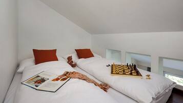 Una camera da letto moderna con due letti, una scacchiera e un libro.