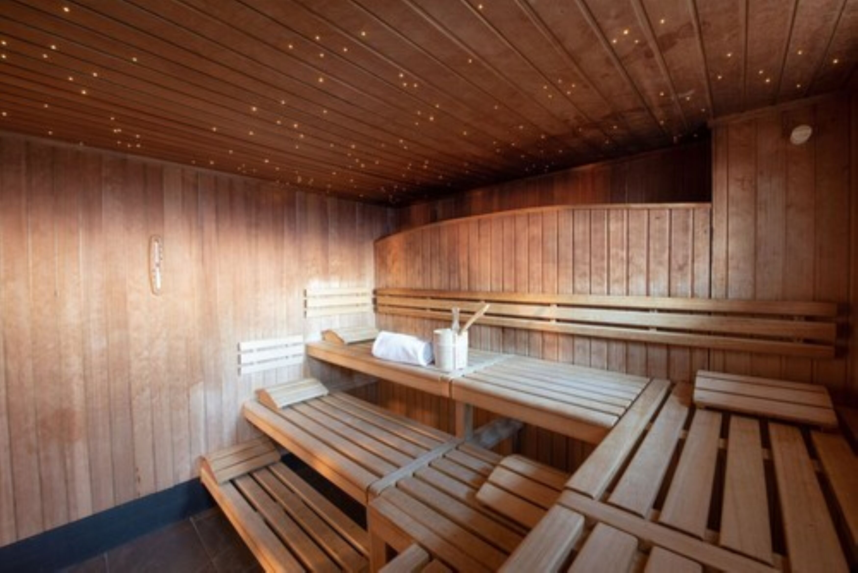 Una sauna con bancos de madera y techo inclinado con luces empotradas.